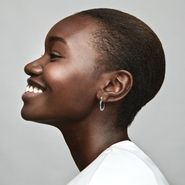 Person smiling in profile wearing a small silver hoop earring.