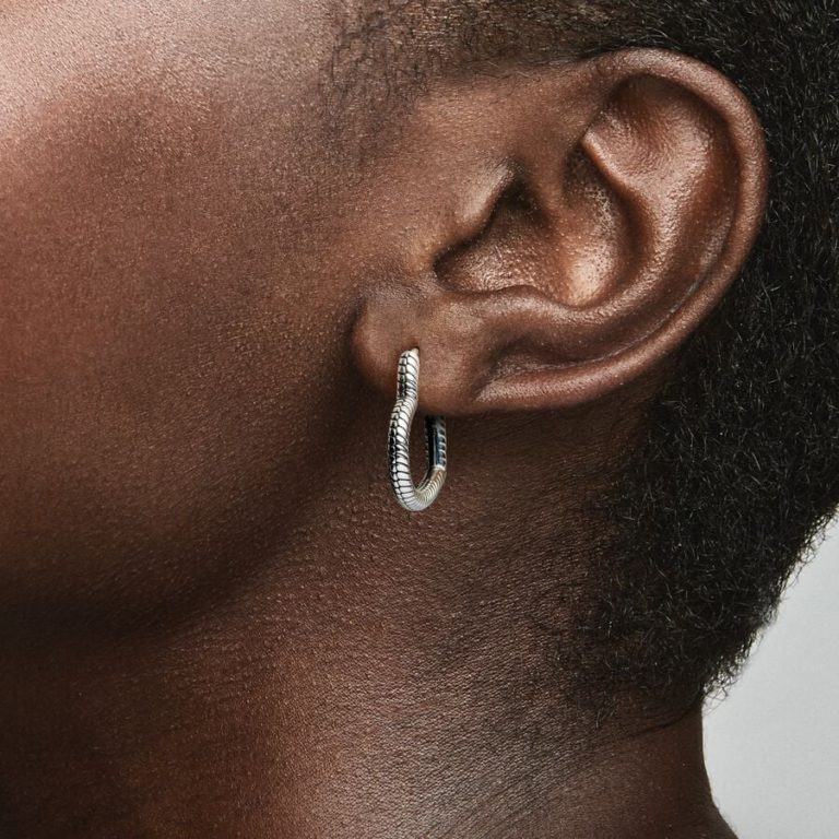 Close-up of an ear wearing a textured silver hoop earring.