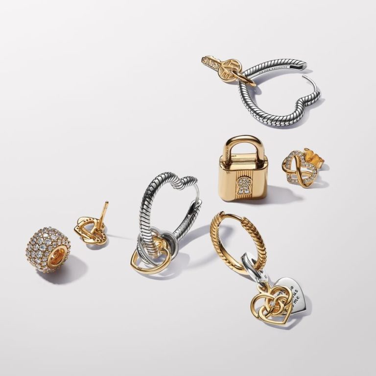 Assorted gold and silver jewelry pieces including hoop earrings, stud earrings, charms, and pendants arranged on a white background.